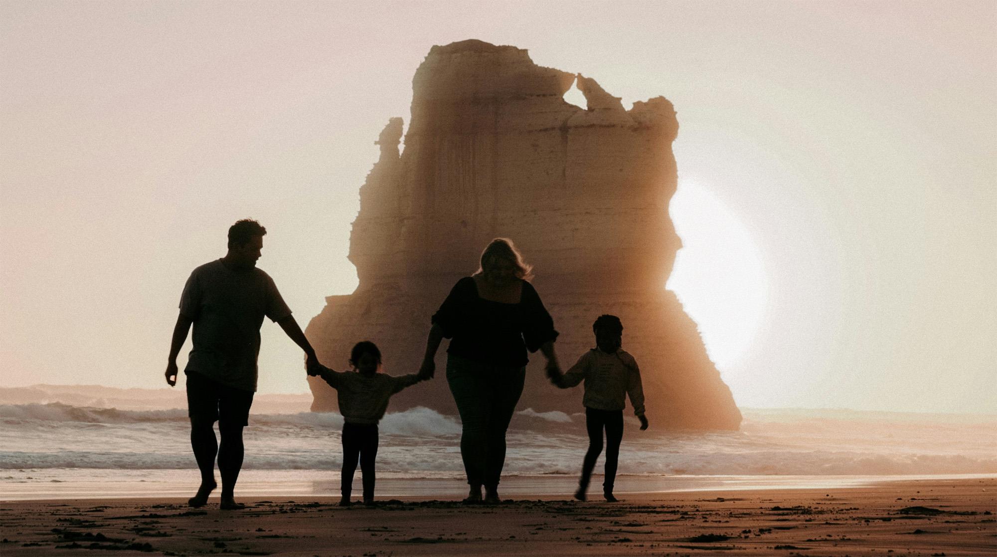 A family walking on the beach, holding hands