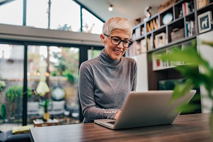 a smart looking middle-aged woman researching on her laptop